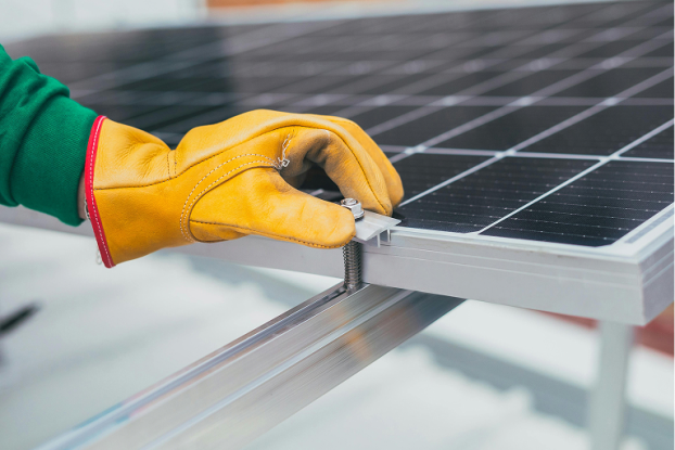 Technicien nettoyant des panneaux photovoltaïques avec équipement professionnel